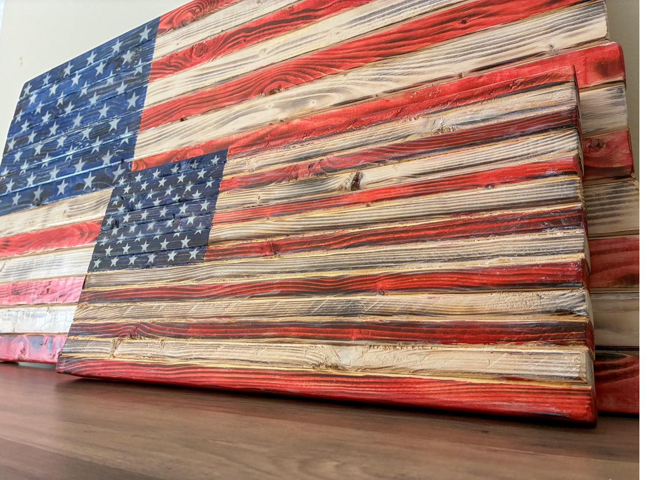 Angled close-up of a handcrafted wood American flag showing the raised three-dimensional hardwood stripes and natural wood grain